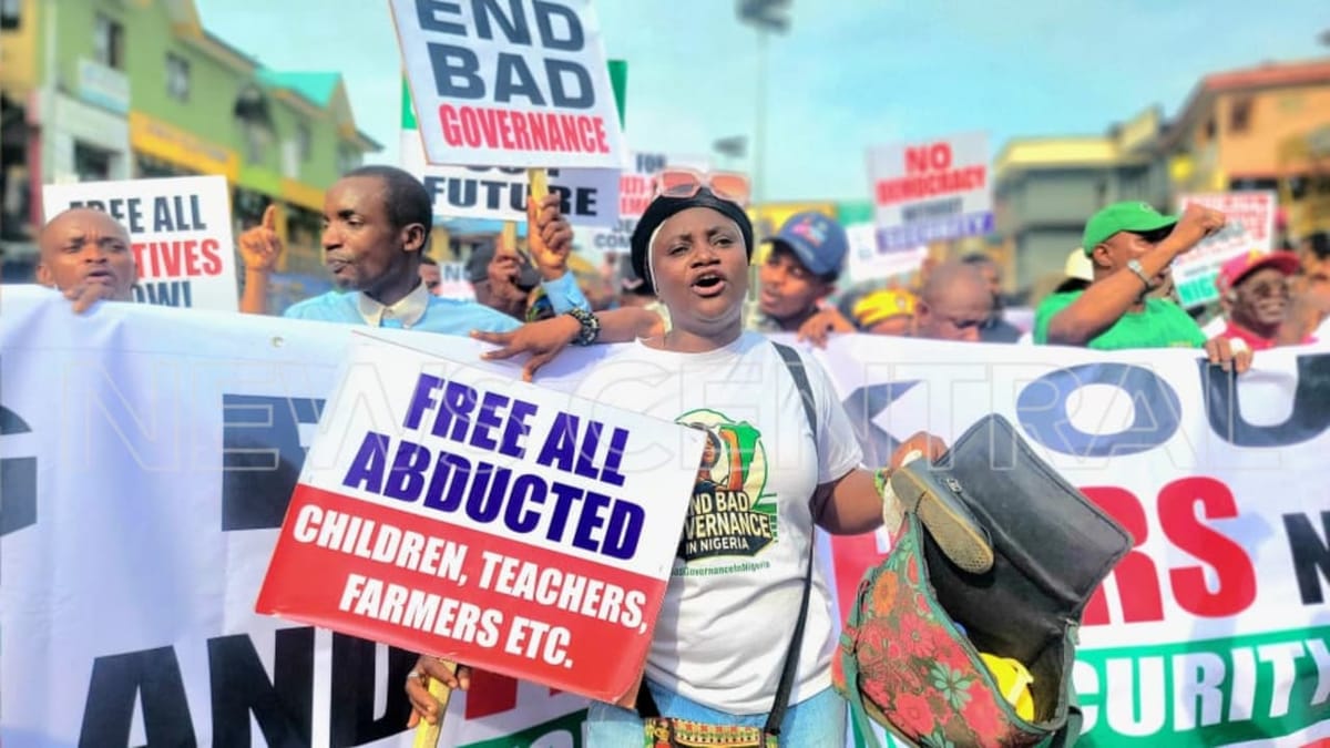 Placards with inscriptions such as 'No Democracy Without Security' and 'End Insecurity and Kidnapping' are displayed during the protest