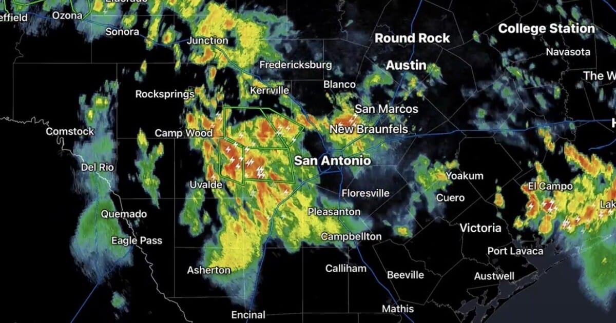 Vehicles navigating a flooded street in San Antonio as heavy rain persists.