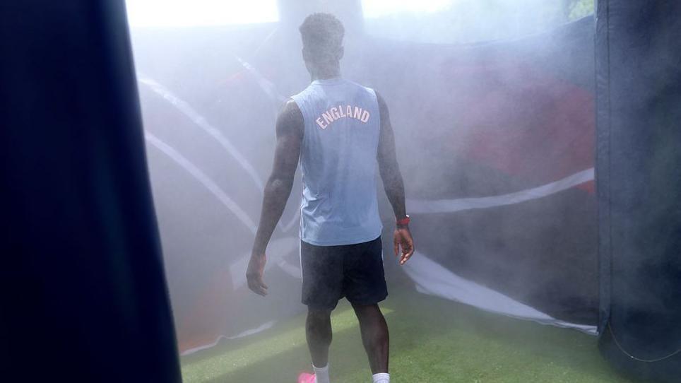 Bukayo Saka of England utilizing a cooling tent during a training session.