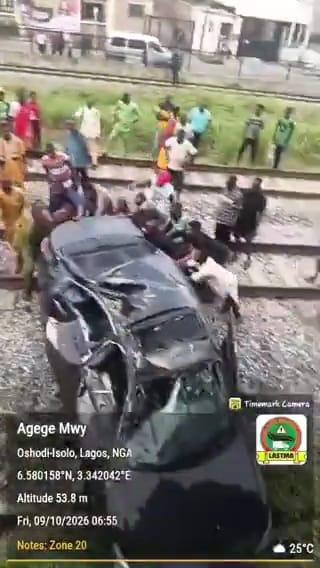 Onlookers assisting to move the mangled Honda vehicle off the train tracks after the accident.