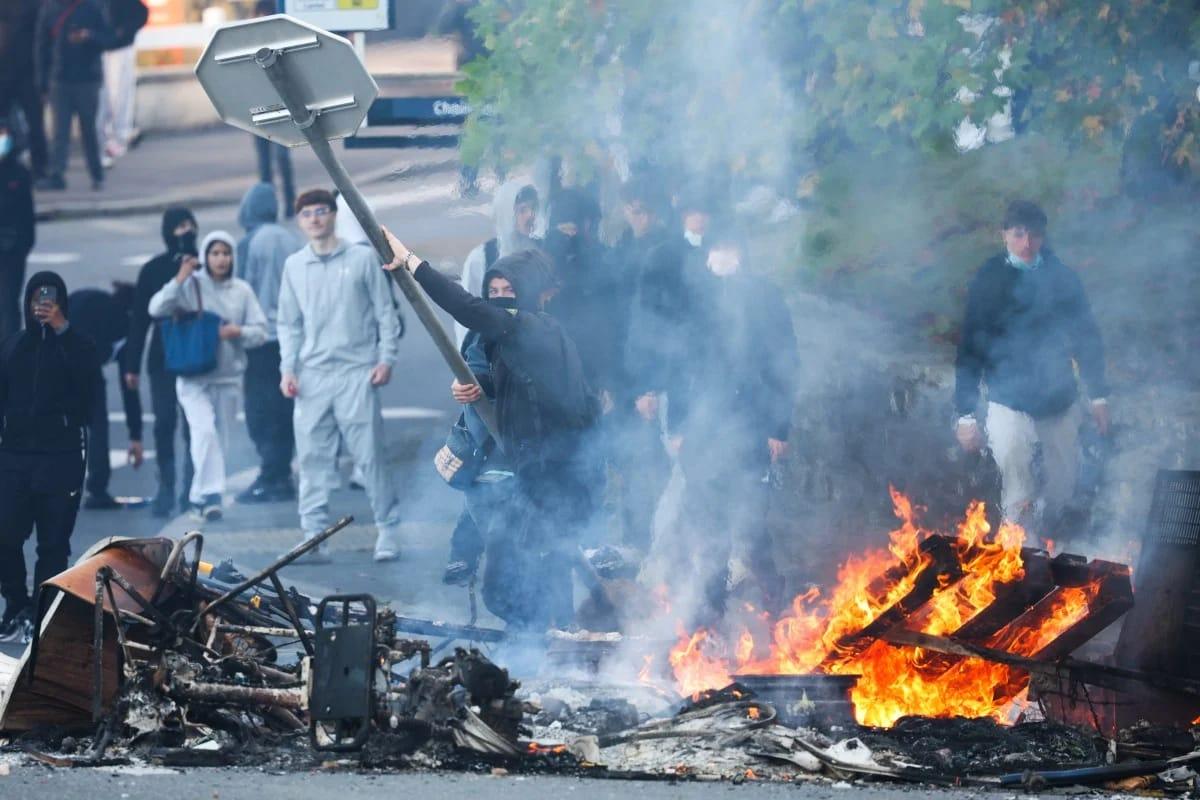 A student protestor throwing a stop sign into a fire during blockading action near Kerichen high school in Brest, western France, on October 2, 2026.