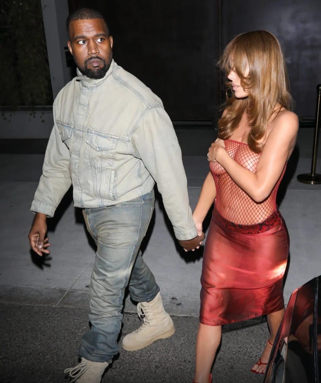 Bianca Censori covering herself while walking with Kanye West.