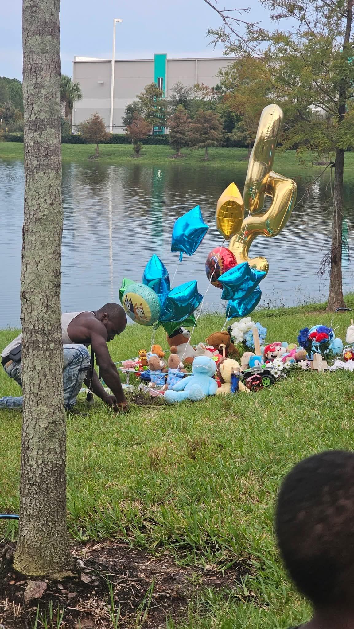A police officer at the scene of an investigation near a body of water in a residential neighborhood.