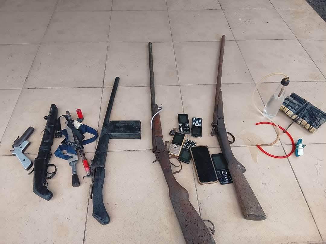 An officer from the Rivers State Police Command standing next to the seized weapons.