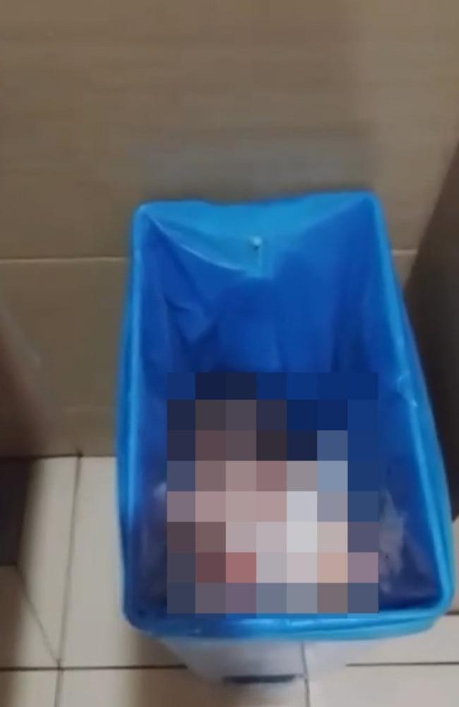 Airport staff carefully lifting the abandoned infant from the trash can to safety.