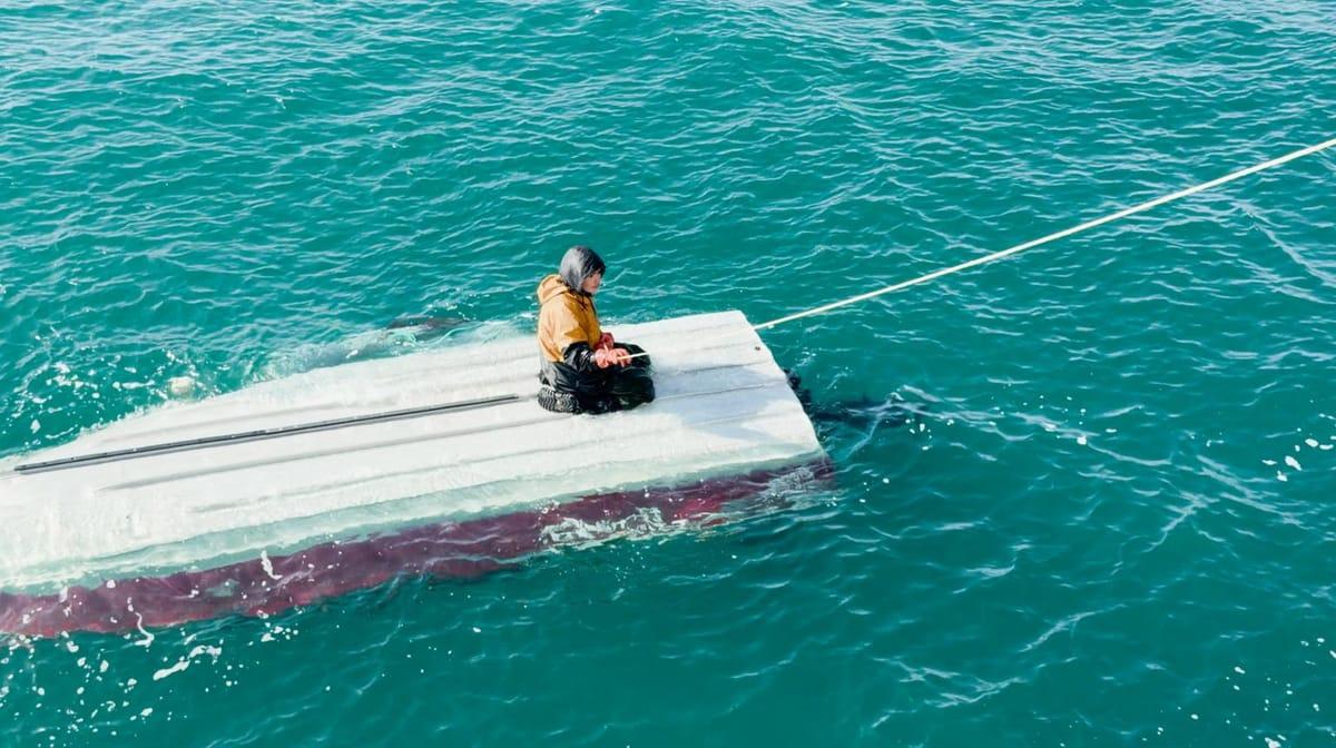 A close-up view of the 15-year-old survivor, Derek Parker Aghnaanga, clinging to the capsized skiff.