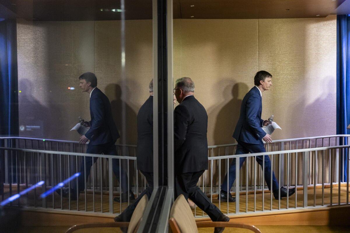 Two men in dark suits walk away from each other, possibly after a meeting or official engagement, symbolizing a disagreement or parting.