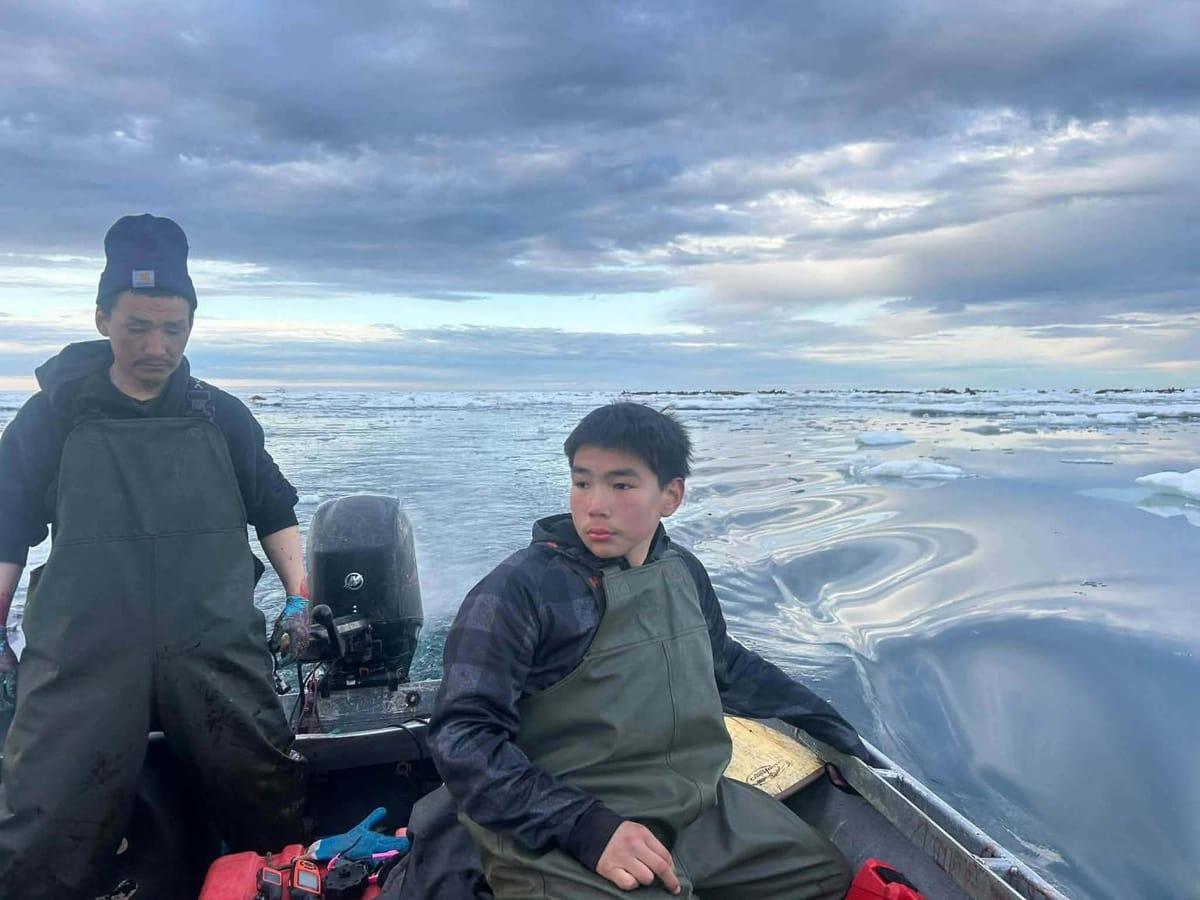 Crew members of the Northwest Explorer assisting the rescued teenager, Derek Parker Aghnaanga, onto their vessel.
