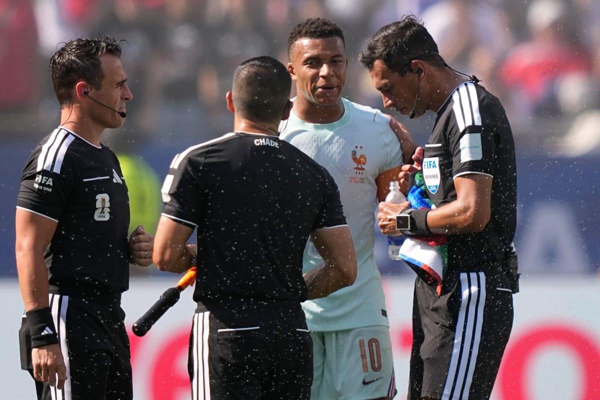France's Kylian Mbappé engages in a discussion with Referee Facundo Tello during a match.