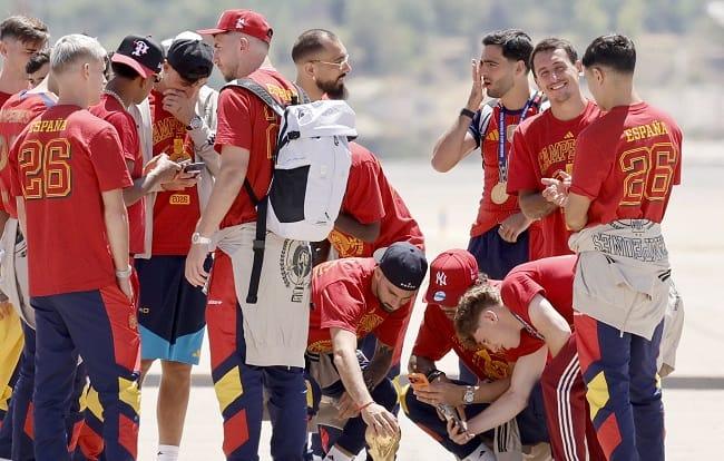 Spanish players disembark from the plane, holding the World Cup trophy