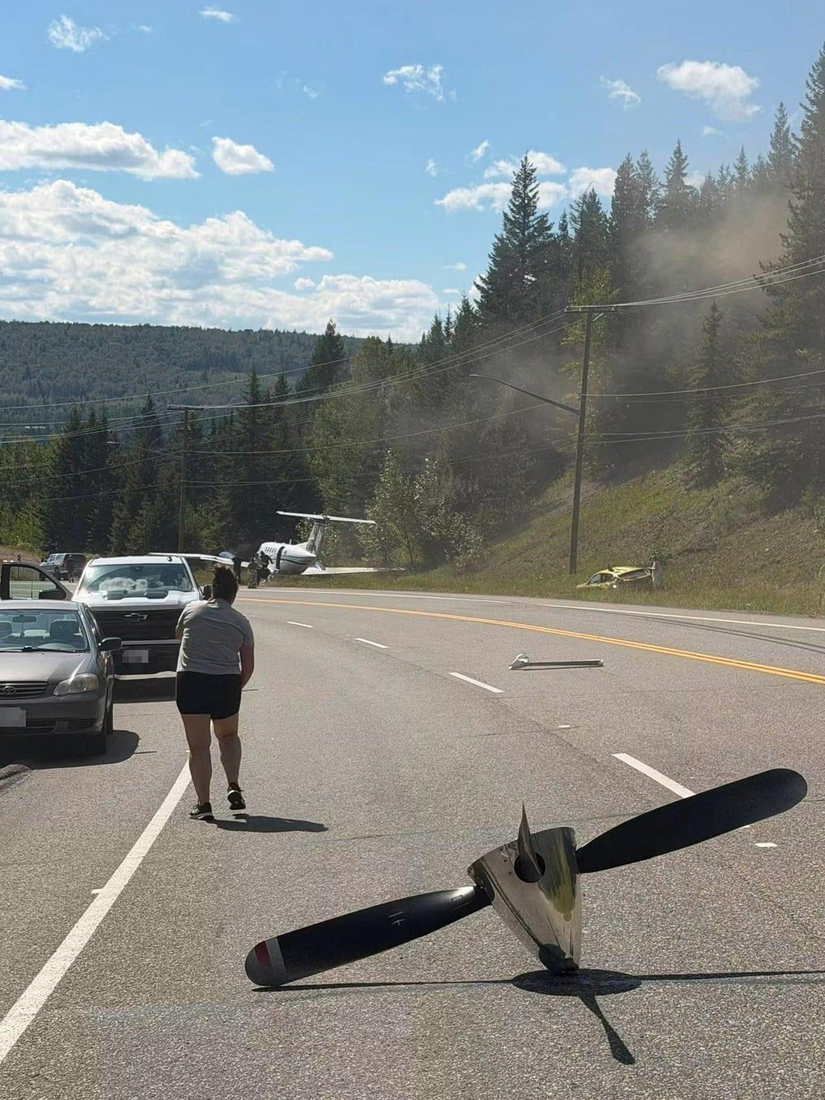 Debris from a damaged car is visible near the rear of the twin-engine aircraft that made an emergency landing.