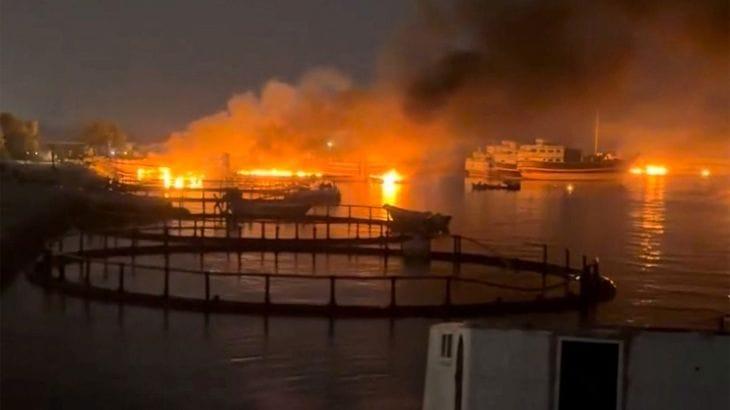 Smoke plumes rising from a port area, believed to be near the strategic Strait of Hormuz, following recent incidents.